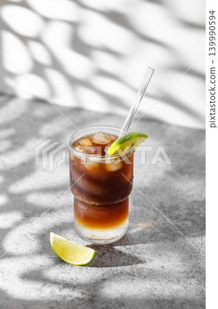 Cold Coffee Tonic Drink With Lime and Ice on light background with shadows Cold Coffee Tonic Drink With Lime and Ice on light background with shadows 139990594
