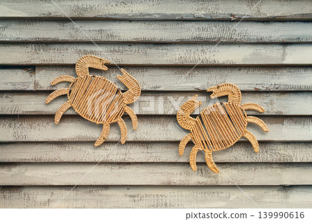 Boho crab wall decoration on wooden plank background with woven straw craft, coastal ornament, handmade texture, copy space. Concept of beach design, summer decor, natural background, boho style 139990616