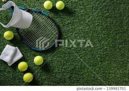 Tennis racket visor and balls on green grass background Tennis racket visor and balls on green grass background 139991701