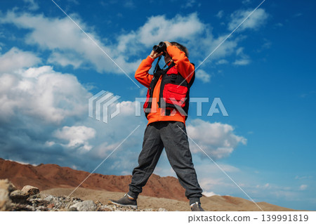 Boy tourist looking in binoculars in mountains Boy tourist looking in binoculars in mountains 139991819