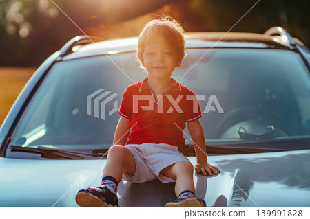 Two-year-old child sits on the hood of the car 139991828