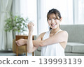 A young woman working out at home, looking directly at the camera. 139993139
