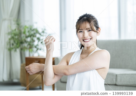 一位年輕女子在家鍛煉，直視鏡頭。 139993139