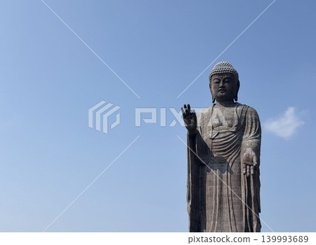 The majestic upper body of the Great Buddha standing against a blue sky. 139993689