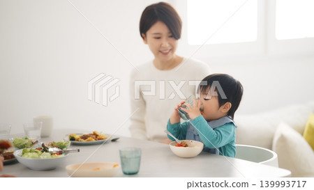 A scene of a family of four eating at the dinner table. A scene of a family of four eating at the dinner table. 139993717