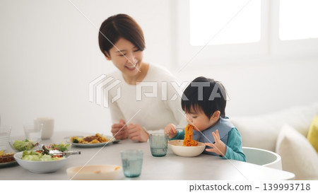 A scene of a family of four eating at the dinner table. 139993718