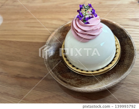 A berry mousse cake garnished with elegant purple flowers. A berry mousse cake garnished with elegant purple flowers. 139993792