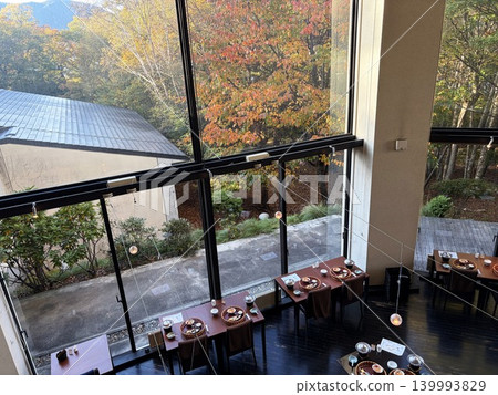 A restaurant with large windows offering views of the autumn foliage. A restaurant with large windows offering views of the autumn foliage. 139993829