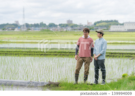 兩名農民站在稻田堤岸上。 兩名農民站在稻田堤岸上。 139994009