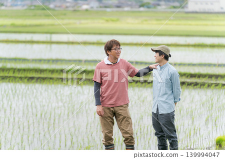 兩名農民站在稻田堤岸上。 139994047