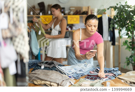 Female shopper checks the quality of jeans or shorts using QR code on label 139994669