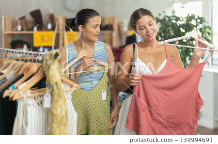 Two positive women choosing something for summer in clothing store Two positive women choosing something for summer in clothing store 139994691