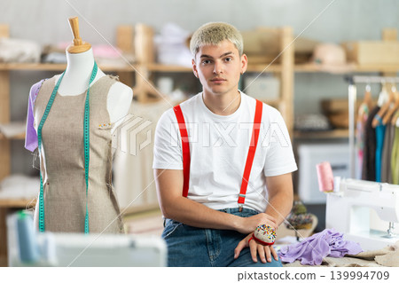 Young male dressmaker posing in sewing workshop Young male dressmaker posing in sewing workshop 139994709