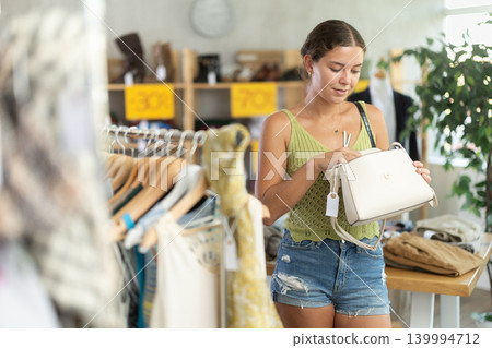 Young woman choosing a fashionable handbag in boutique Young woman choosing a fashionable handbag in boutique 139994712