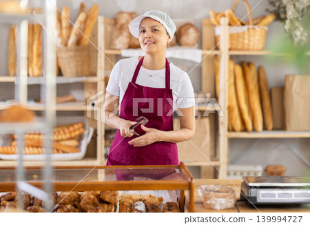 Asian woman bakery worker sells croissants, stand at counter and wait for visitors 139994727