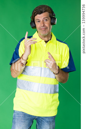 Adult man in reflective polo shirt listening to music and dancing on green screen Adult man in reflective polo shirt listening to music and dancing on green screen 139994736
