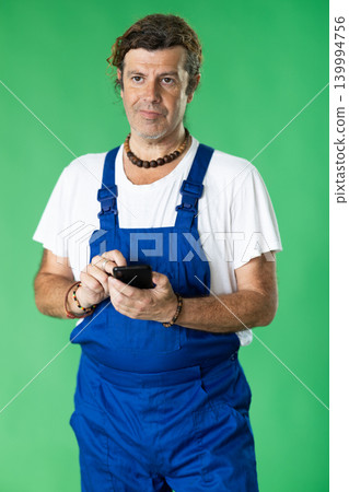 Handyman in overalls responds to customer messages on green background 139994756
