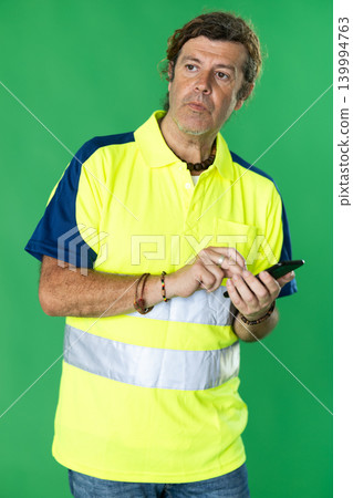Utility worker in a reflective polo shirt with mobile phone on a chroma key Utility worker in a reflective polo shirt with mobile phone on a chroma key 139994763