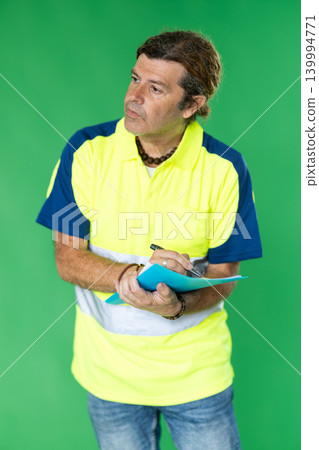 Employee in special reflective clothing on a green background Employee in special reflective clothing on a green background 139994771