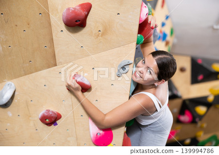 Young woman practicing rock climbing on climbing wall 139994786