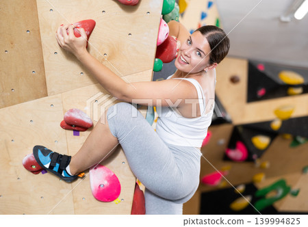 Woman training at bouldering gym without special climbing equipment 139994825