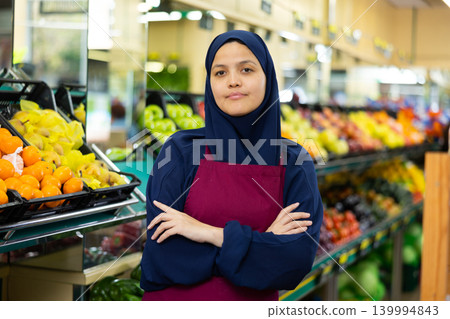 Portrait of friendly female salesperson in hijab and apron in grocery section of supermarket 139994843