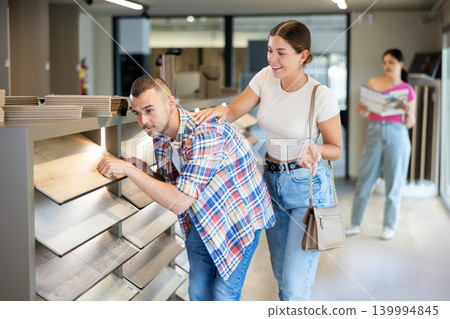 Young married couple chooses laminate flooring together in hardware store Young married couple chooses laminate flooring together in hardware store 139994845