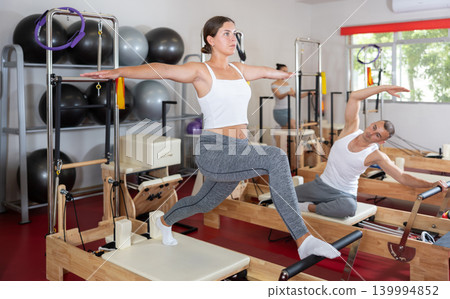 Young woman doing stretching on pilates reformer Young woman doing stretching on pilates reformer 139994852