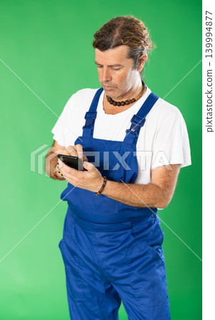 Handyman in overalls responds to customer messages on green background 139994877