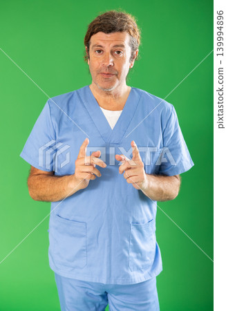 Man in blue surgery suit on green screen background speaks to imaginary partner. Man in blue surgery suit on green screen background speaks to imaginary partner. 139994896