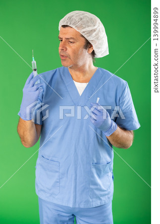 Adult male medic explaining injection procedure with syringe on green screen 139994899