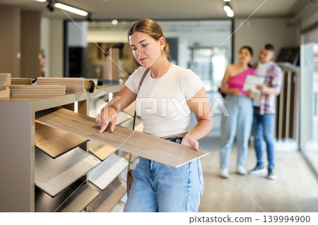 Female buyer chooses laminate flooring in hardware store 139994900
