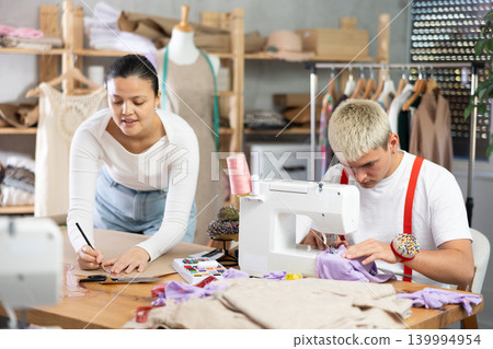 Tailors sew clothes and draw designs Tailors sew clothes and draw designs 139994954