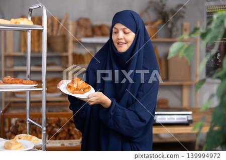 Asian Muslim girl in hijab customer holding disposable plate with burger snack in bakery 139994972