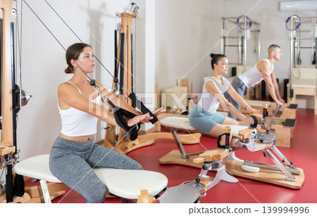 Sportive young girl training her arms pulling handle of cable exercise machine 139994996