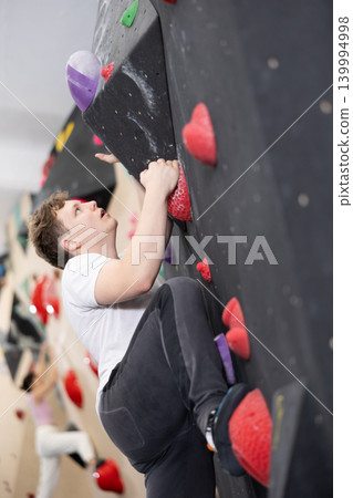 Teenage boy climbs steep artificial wall in sports complex and trains endurance Teenage boy climbs steep artificial wall in sports complex and trains endurance 139994998