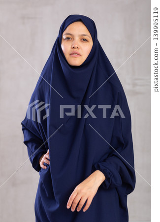 Portrait of young positive woman in khimara posing in studio 139995119