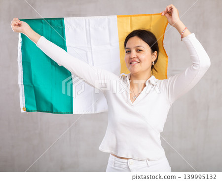 Pretty young female student holding Ireland flag in her hands Pretty young female student holding Ireland flag in her hands 139995132