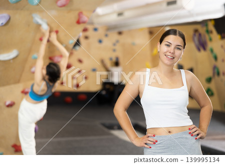 Young woman posing against climbing wall Young woman posing against climbing wall 139995134