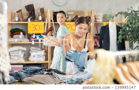 Young woman choosing jean shorts in clothing store Young woman choosing jean shorts in clothing store 139995147