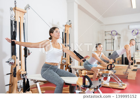 Sportive young girl training her arms pulling handle of cable exercise machine Sportive young girl training her arms pulling handle of cable exercise machine 139995152