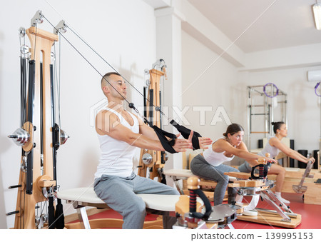 Young man training his arms using straps Young man training his arms using straps 139995153