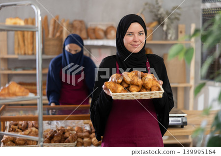 Smiling Muslim saleswoman presenting fresh pastries in bakery 139995164