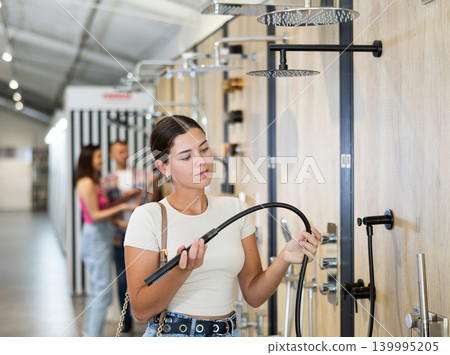 Female buyer choosing shower head in hardware store 139995205