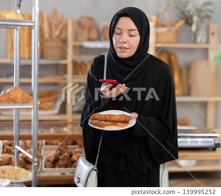 Muslim woman using phone and counting calories Muslim woman using phone and counting calories 139995252