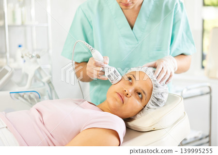 Young male cosmetologist doing whitening procedure to young woman Young male cosmetologist doing whitening procedure to young woman 139995255