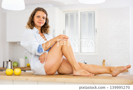 Portrait of young girl sitting on table, side view Portrait of young girl sitting on table, side view 139995270