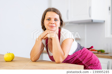 Portrait of woman in apron posing near table Portrait of woman in apron posing near table 139995285