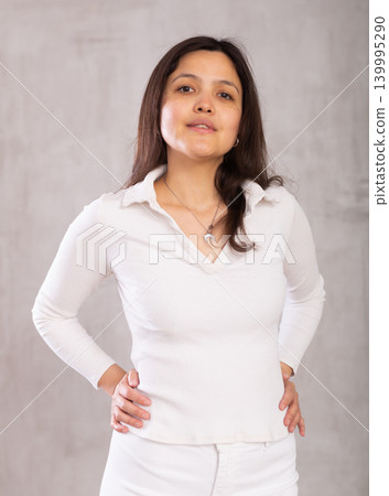 Young slender woman in light casual clothes put hands on waist and smiles sincerely Young slender woman in light casual clothes put hands on waist and smiles sincerely 139995290
