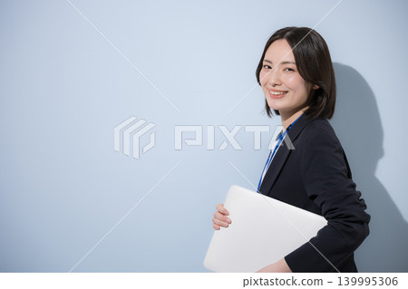 一位可愛的女員工,戴著名牌,手持筆記型電腦,背景是淺藍色背景,代表商業和IT形象。 一位可愛的女員工,戴著名牌,手持筆記型電腦,背景是淺藍色背景,代表商業和IT形象。 139995306